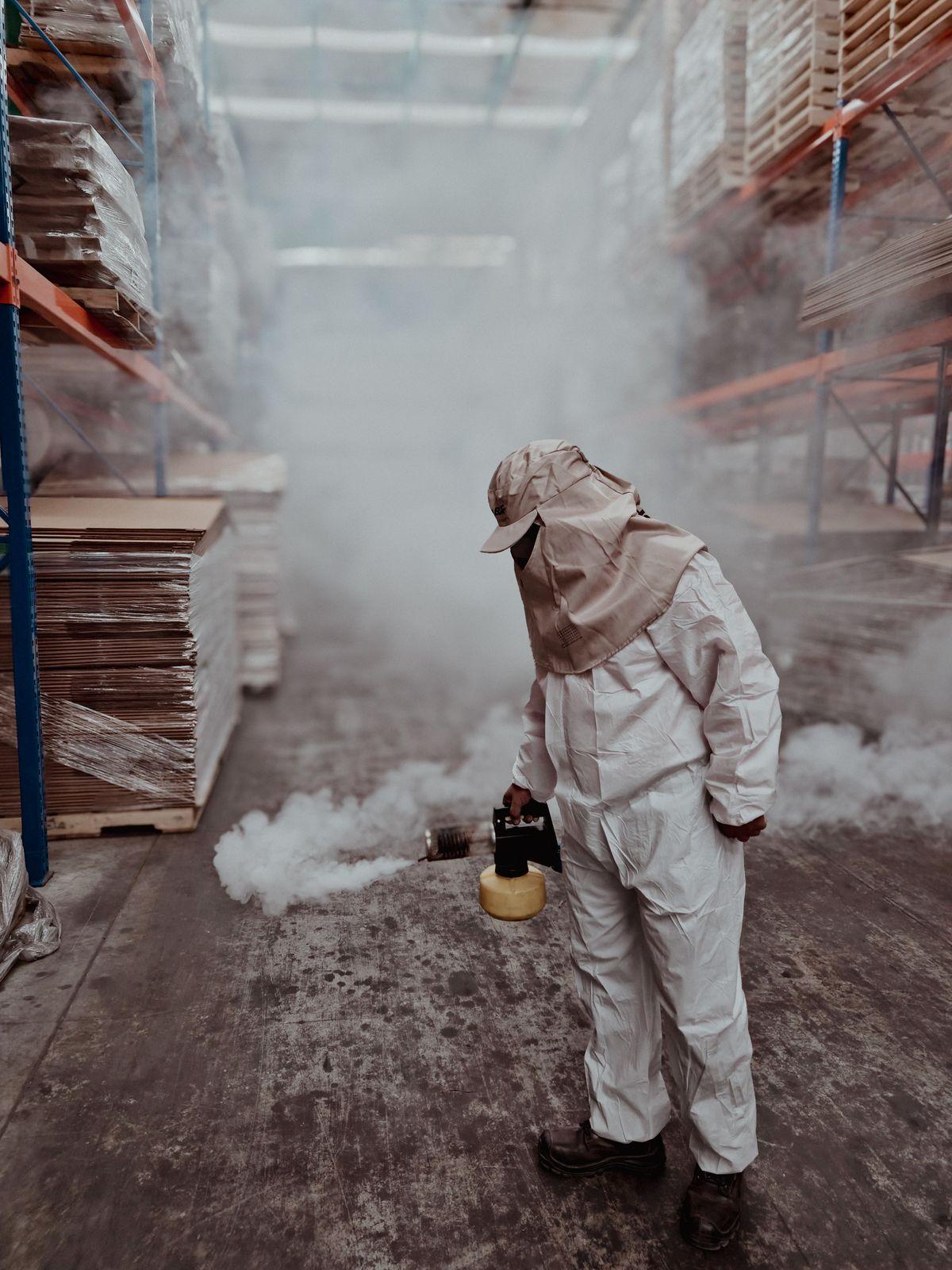 Técnico aplicando fumigación profesional en una bodega
